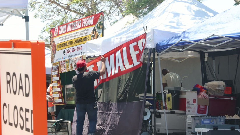 Worker Putting Up Tamales Sign